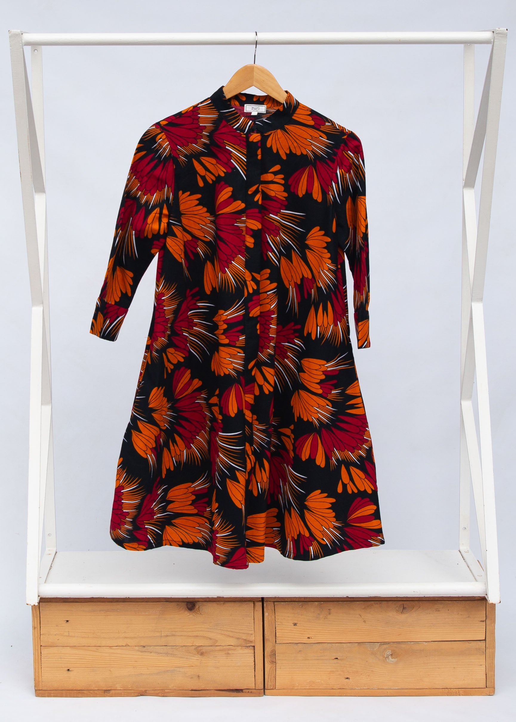 Display of black dress with orange, red and white floral print.