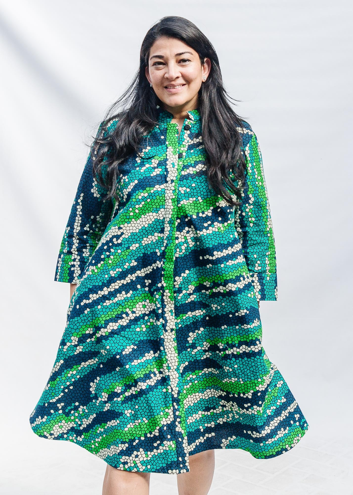 The model is wearing black, green, white, blue and aqua print dress
