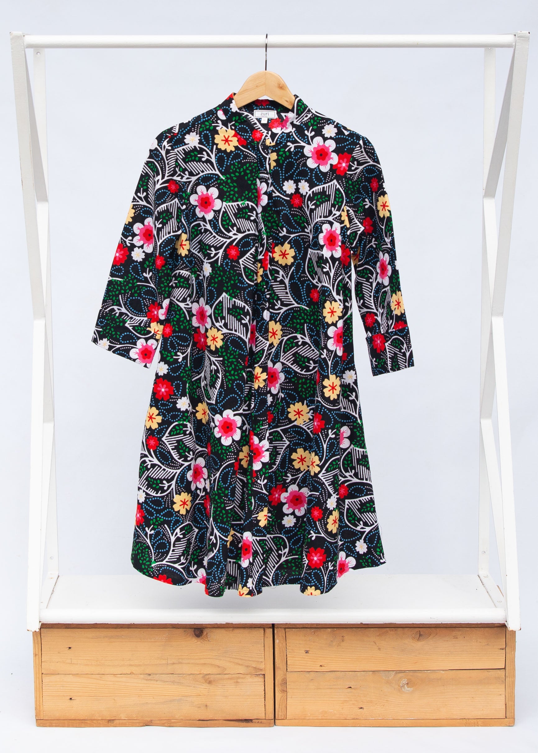 Display of black dress with white, green, red and yellow floral print.