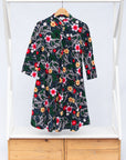 Display of black dress with white, green, red and yellow floral print.