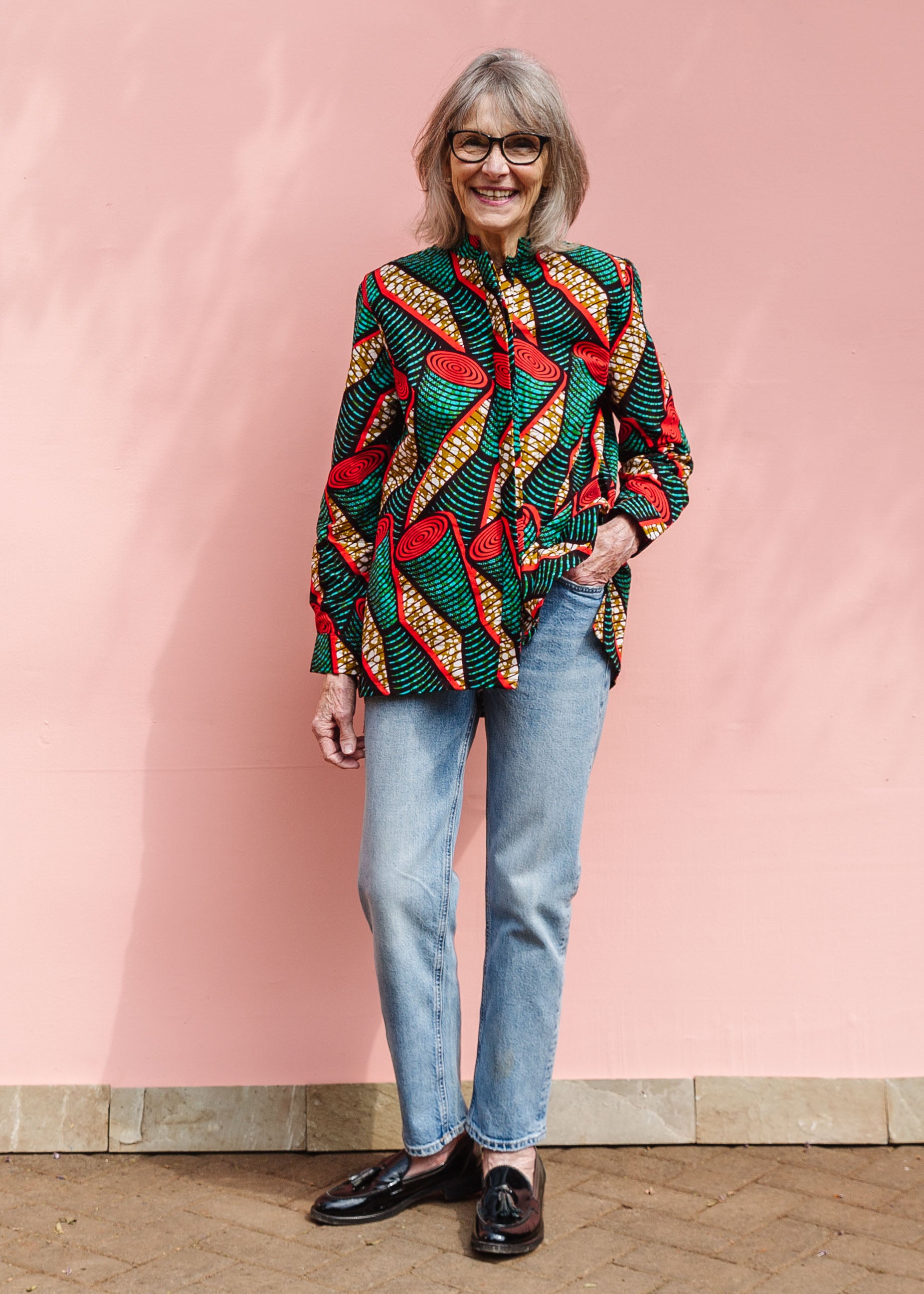 Model wearing green, red, black and brown scroll print long sleeve blouse.