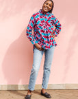 Model wearing pink, red, blue and black tube print long sleeve blouse.