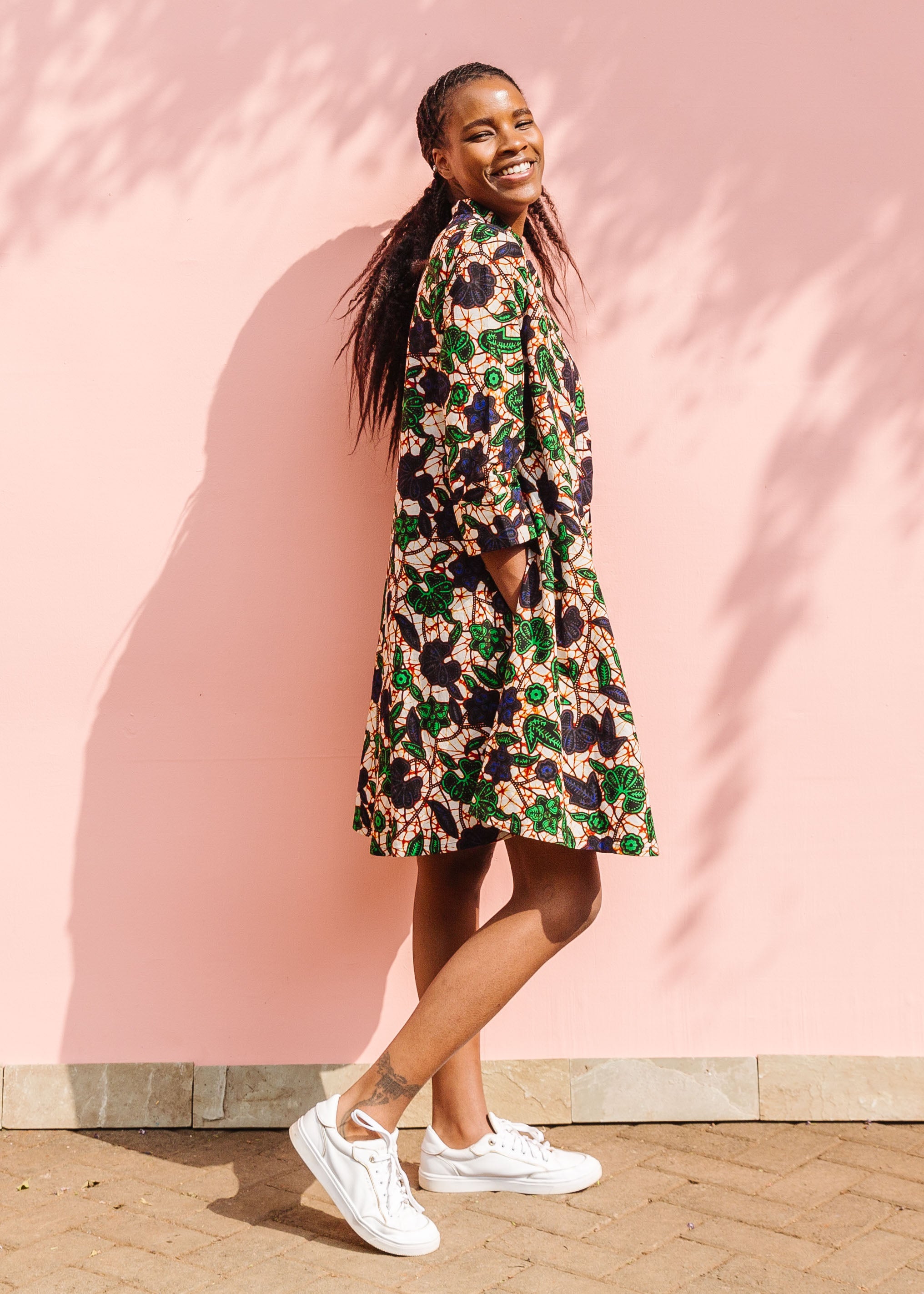 Model wearing brown dress with green and blue vine print.