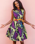 The model is wearing yellow-green dress with purple, black, white fish print 