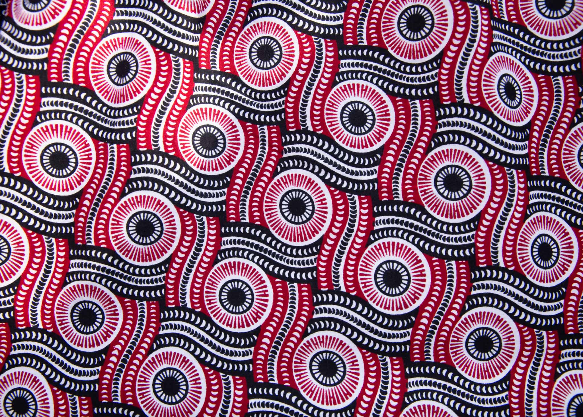 Close up display of long sleeve blouse with black, red, and white circles, fabric.
