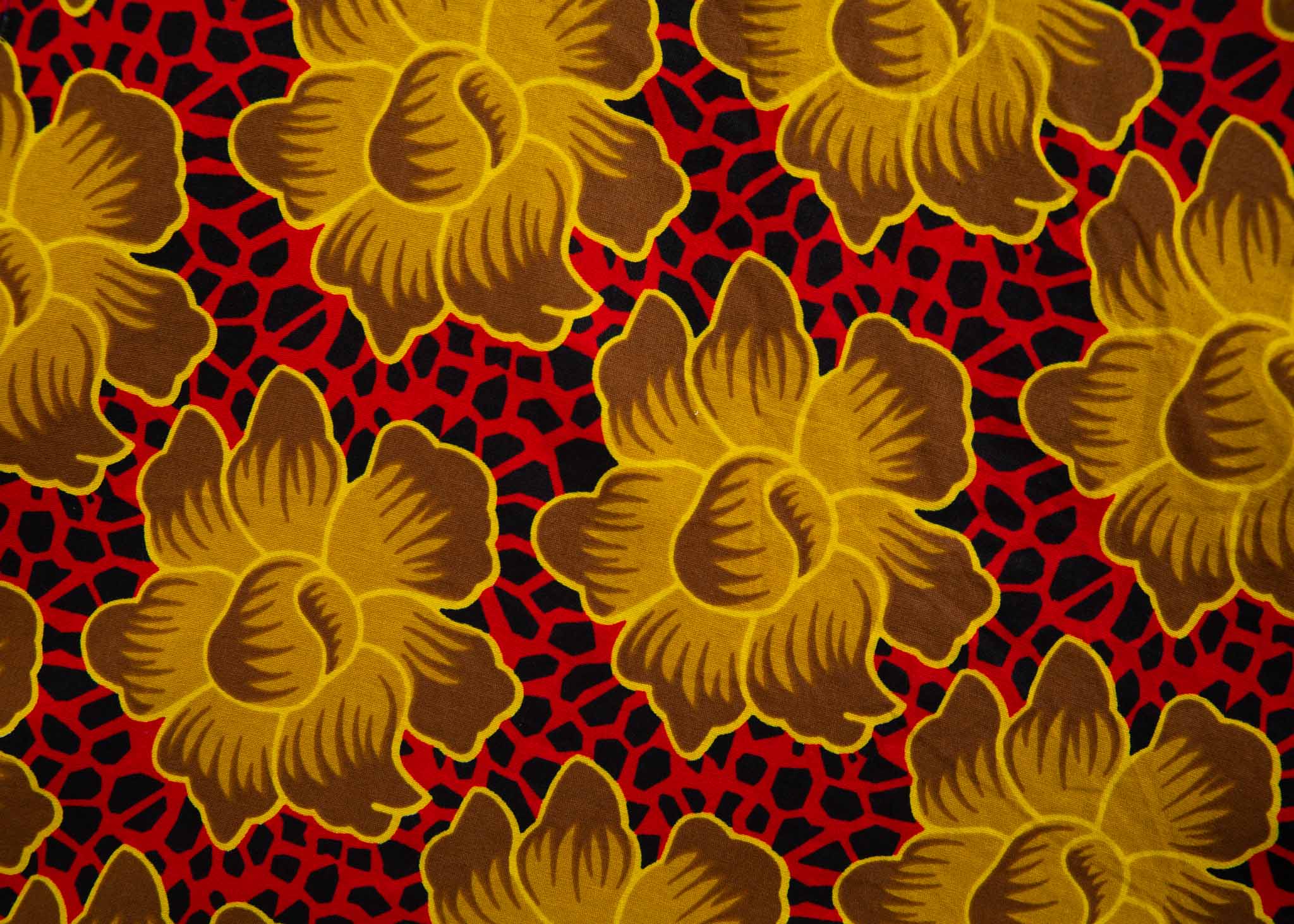 Close up display of red dress with yellow and brown flowers, fabric.