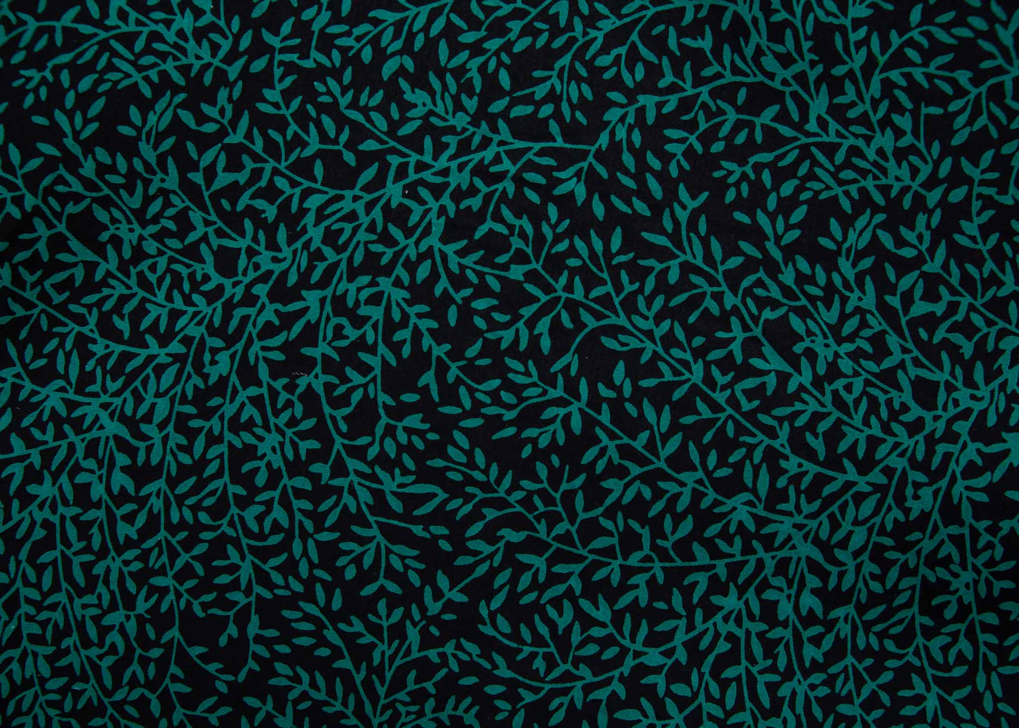 Close up display of black and green dress with small vine print, fabric.