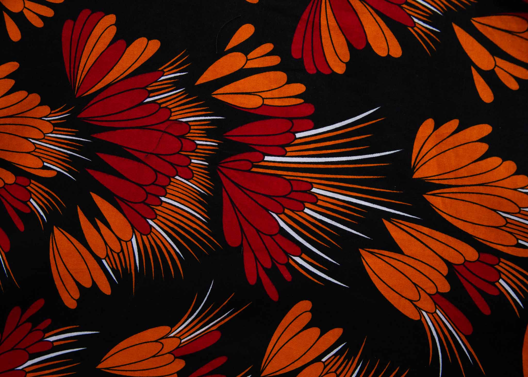 Close up Display of black dress with orange, red and white floral print, fabric.