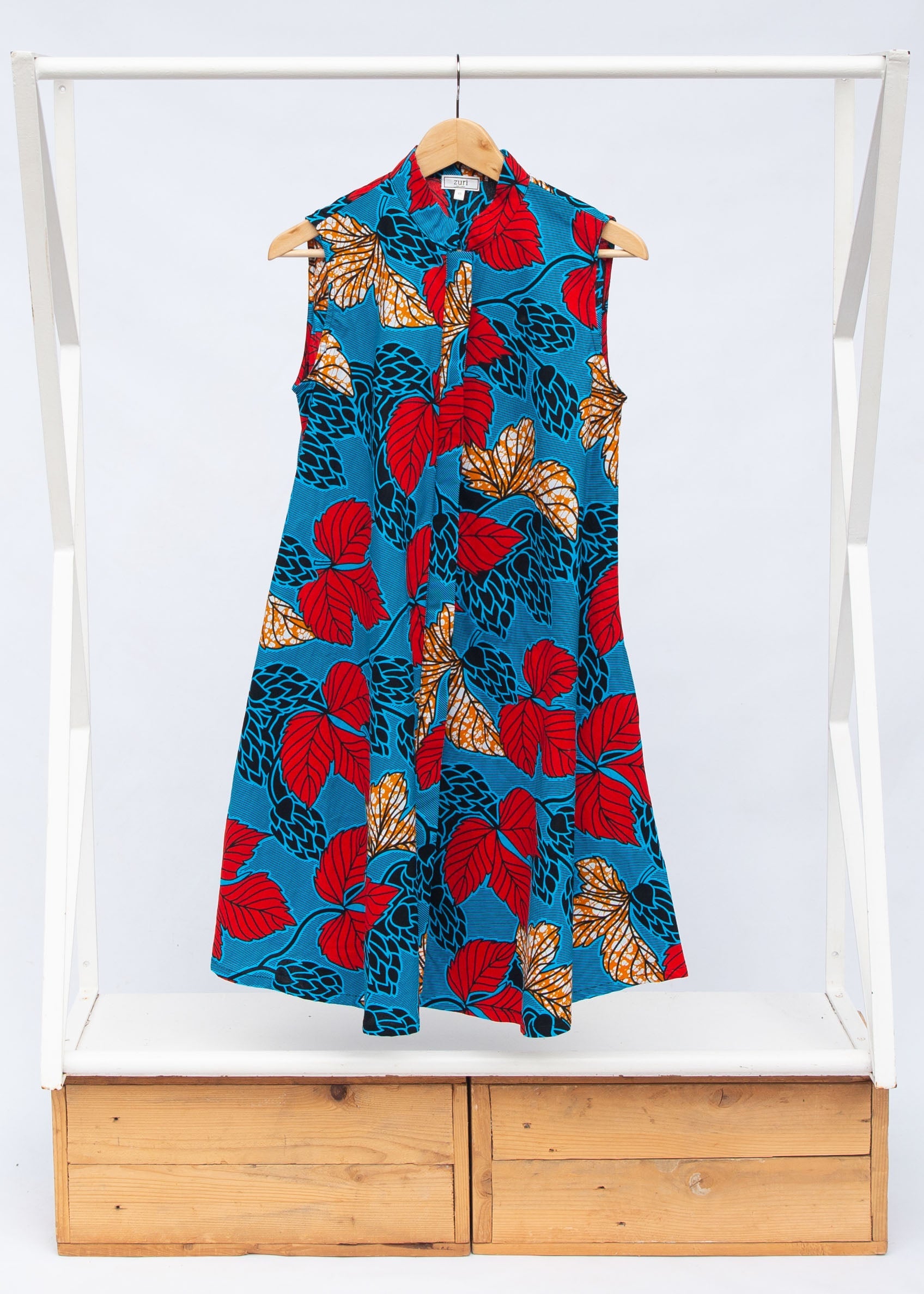 Display of blue sleeveless dress with red and orange leaf print.