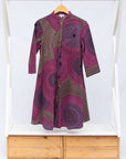 Display of purple dress with pink and beige dotted circle print, fabric.