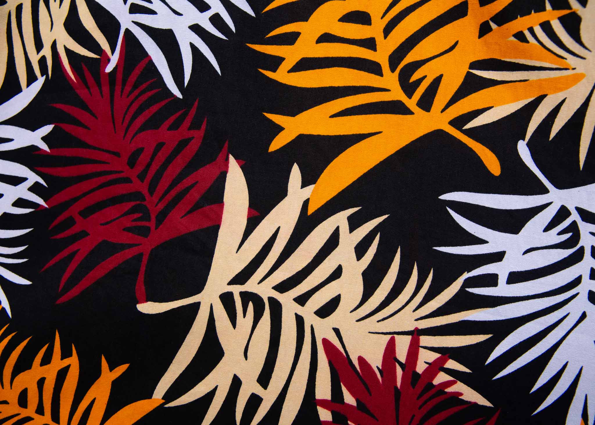Close up display of black dress with orange, red and white leaf print, fabric.