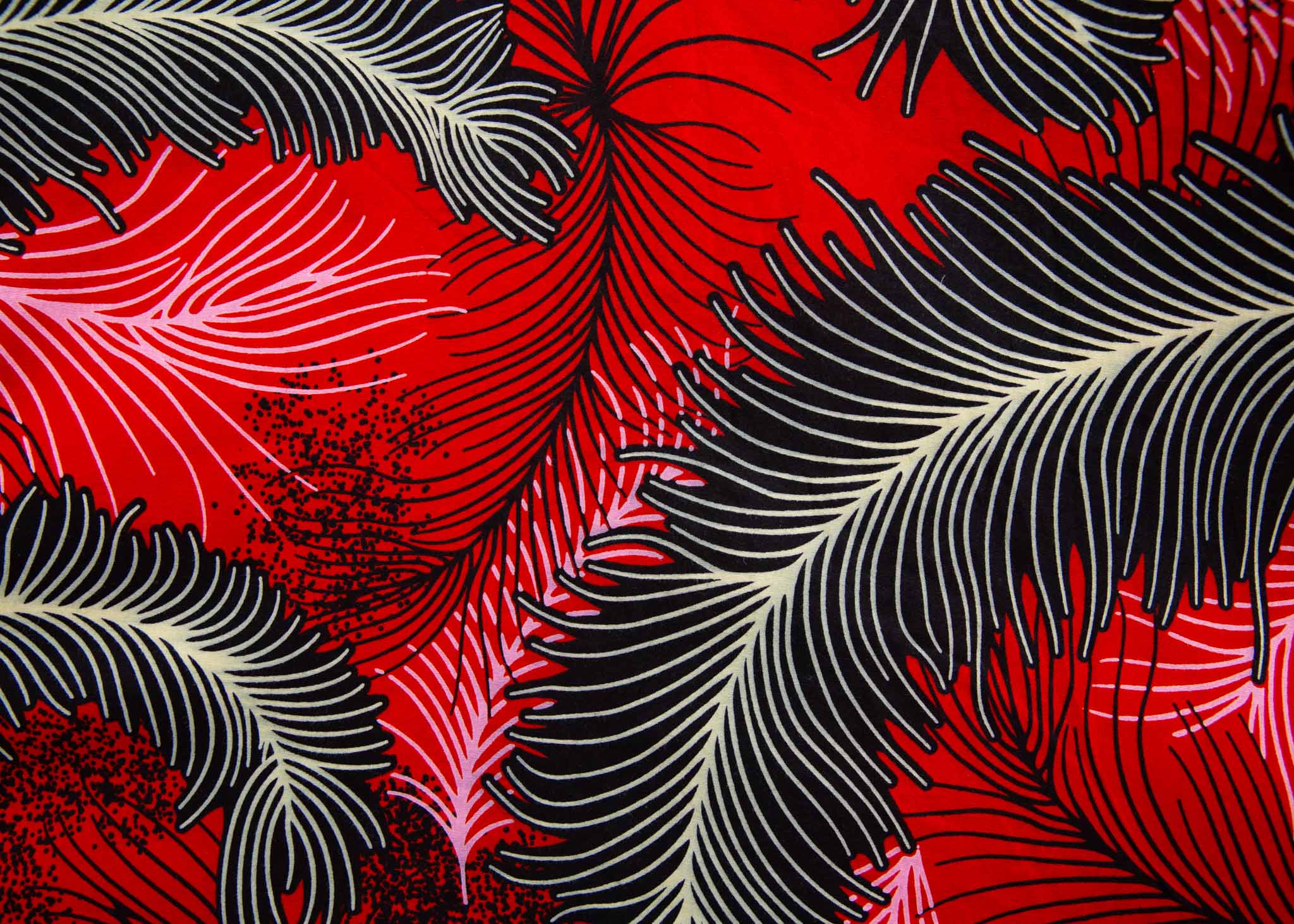 Close up display of red dress with black and white feather print, fabric.