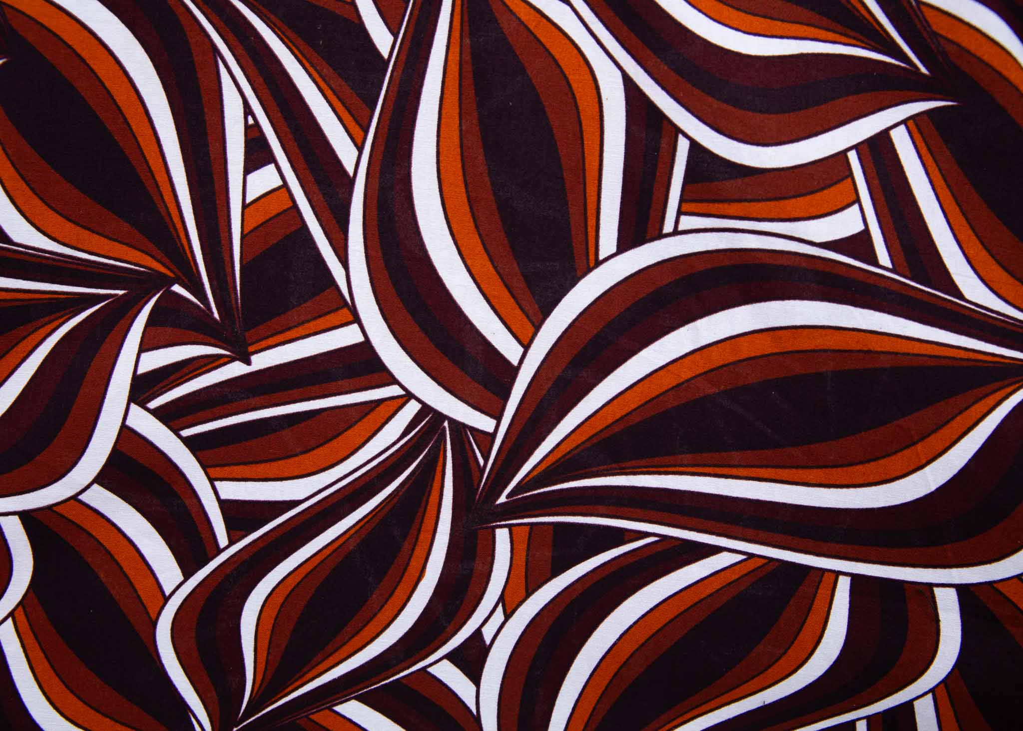 Close up display of brown, orange, burgundy and white abstract print dress, fabric.