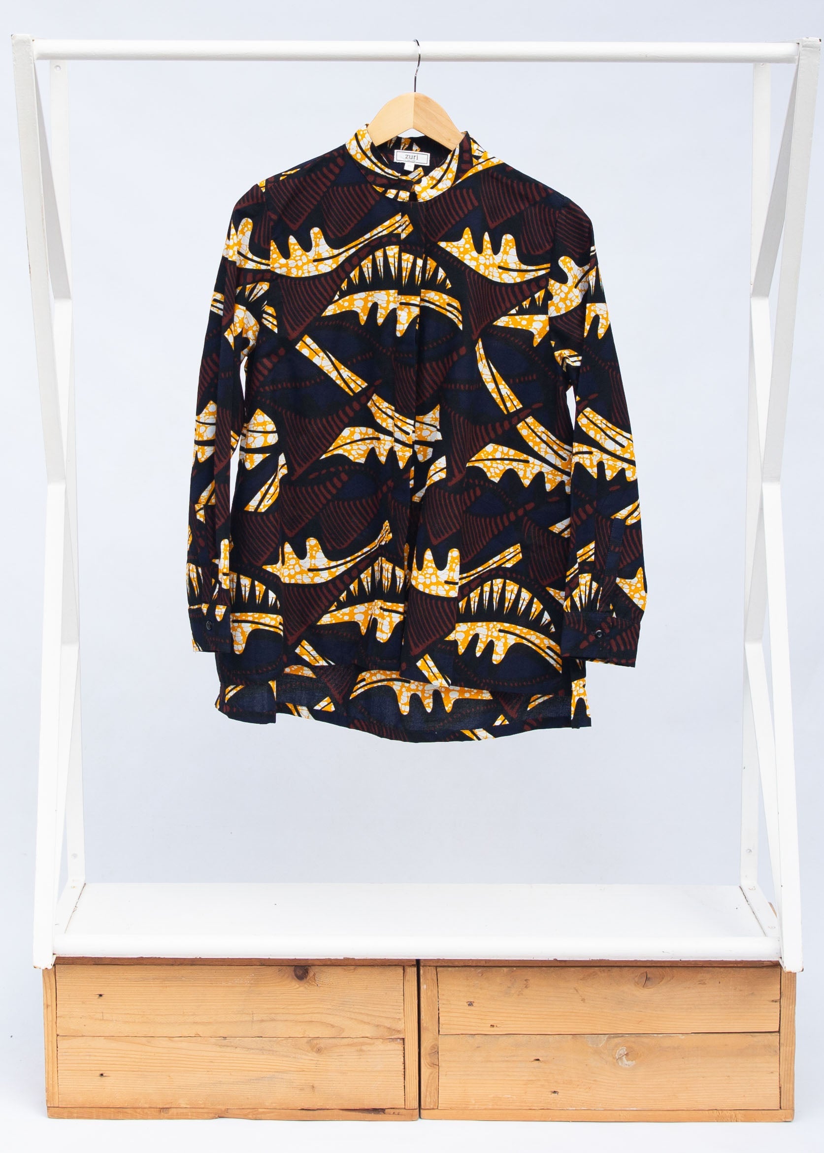Display of long sleeve blouse with brown and yellow abstract print.