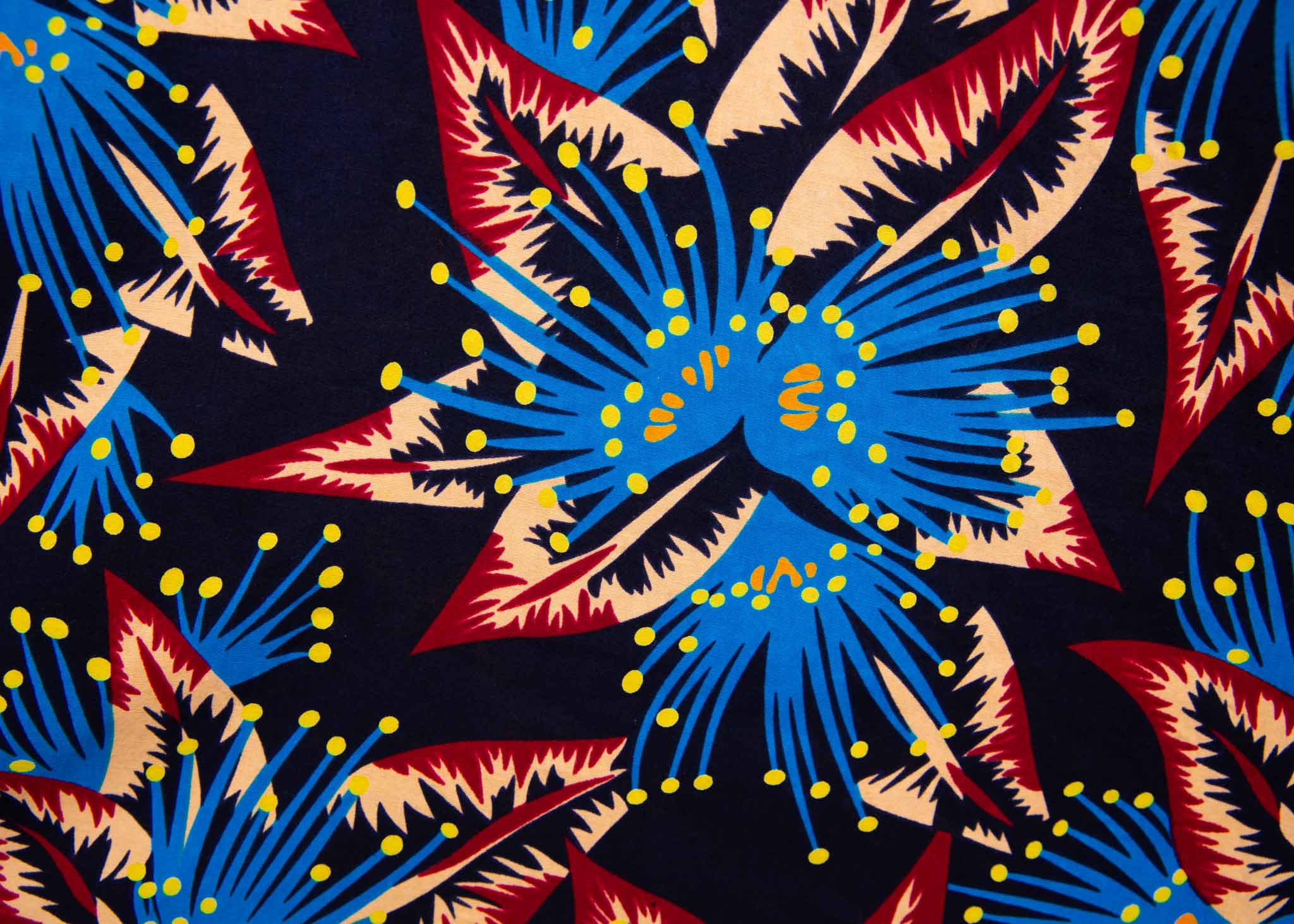Close up display of black dress with blue, beige and red splatter print, fabric.