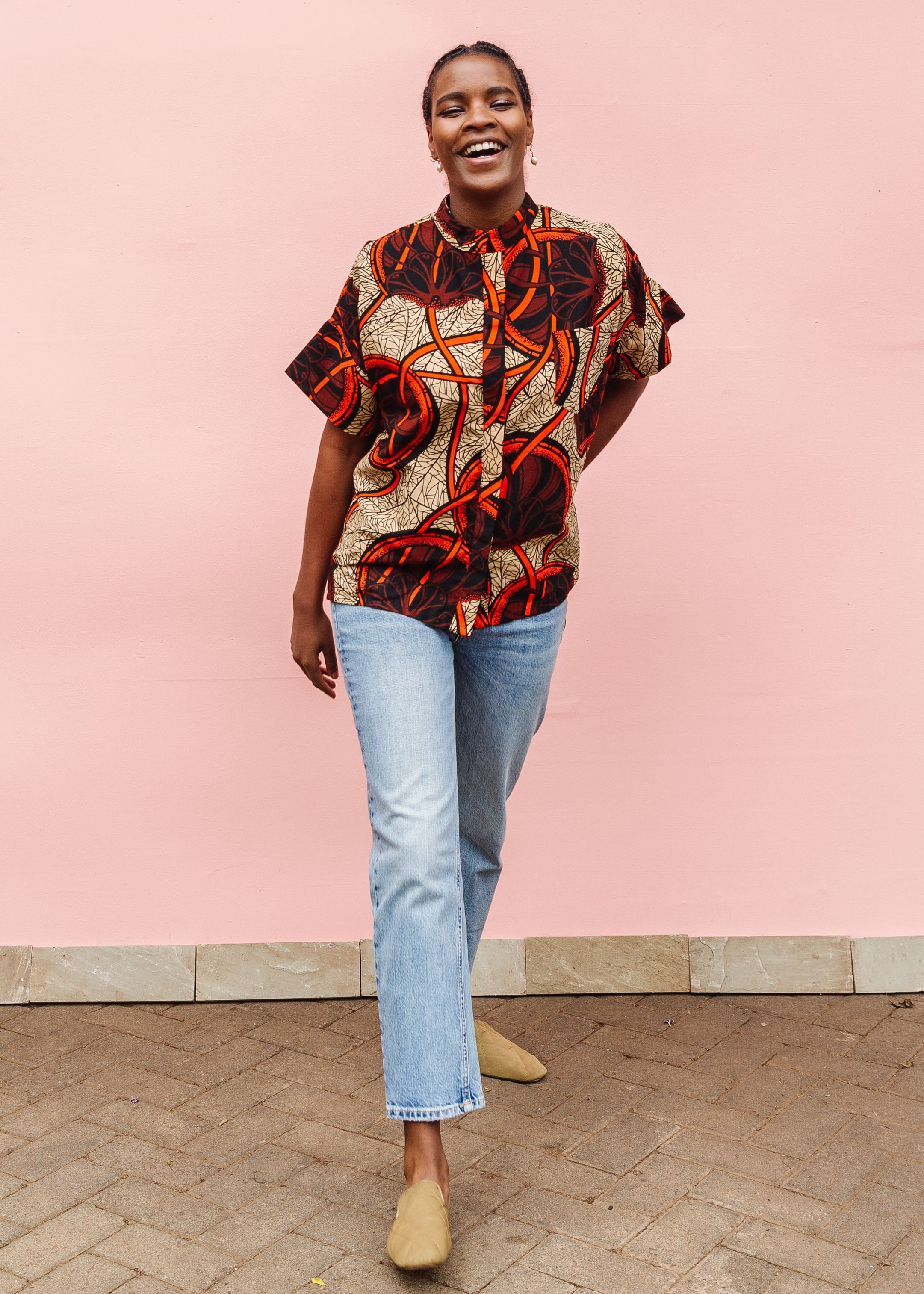 Model wearing beige shirt with brown and orange circles and lines.