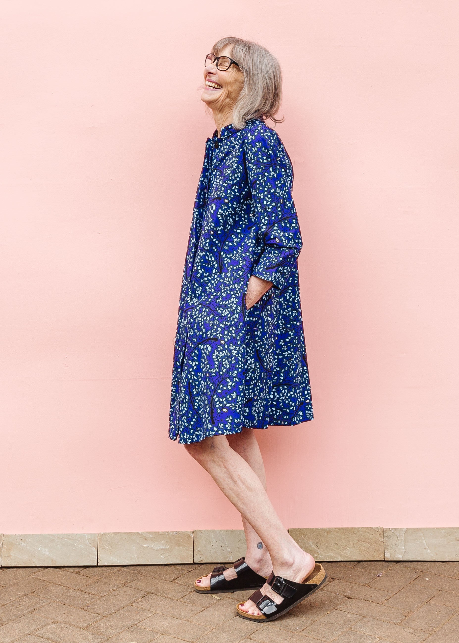 Model wearing blue dress with small vine print.