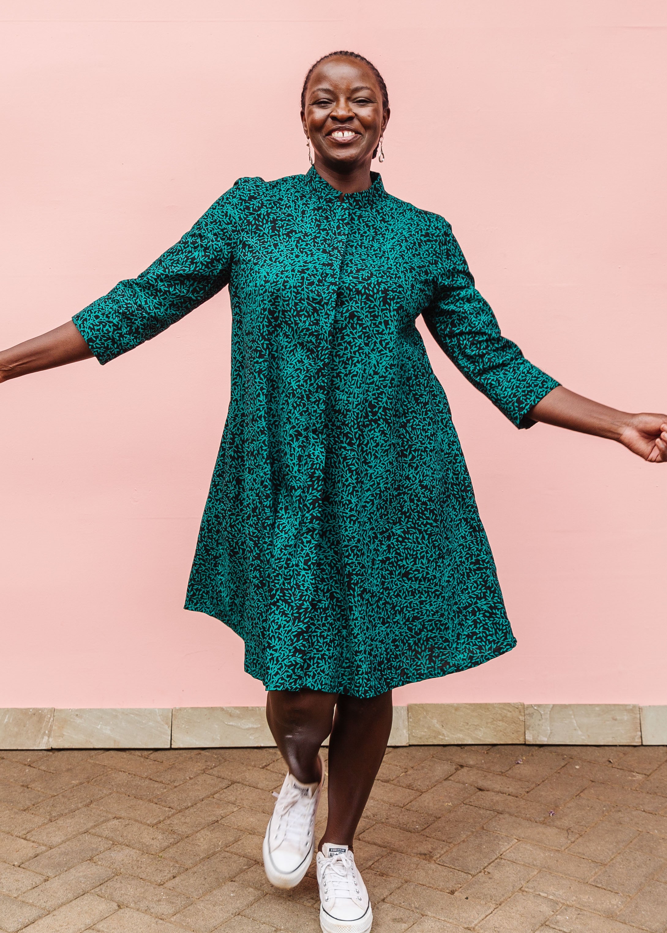 Model wearing black and green dress with small vine print.