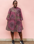 Model wearing purple dress with pink and beige dotted circle print.