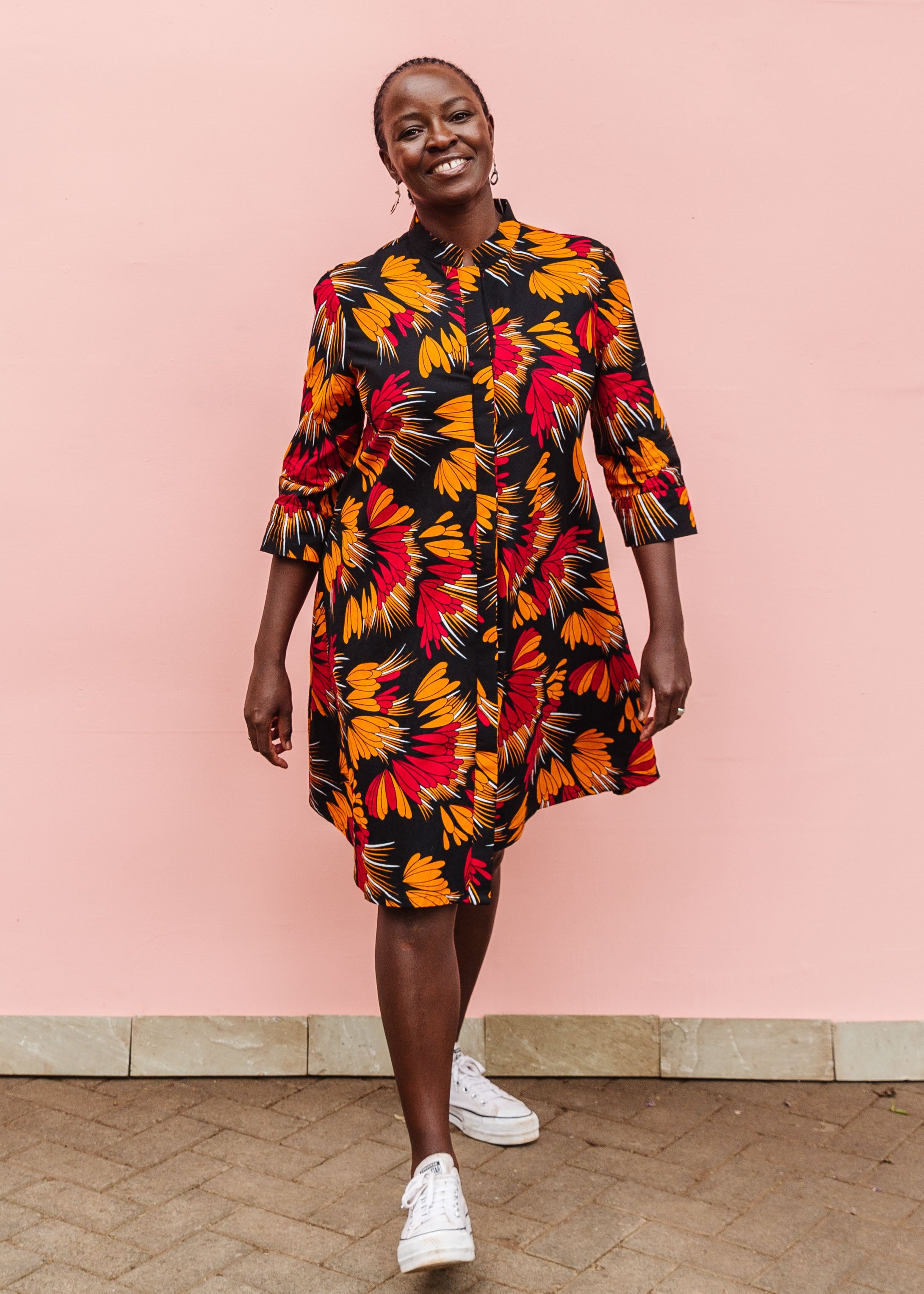Model wearing black dress with orange, red and white floral print.