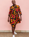 Model wearing black dress with orange, red and white floral print.