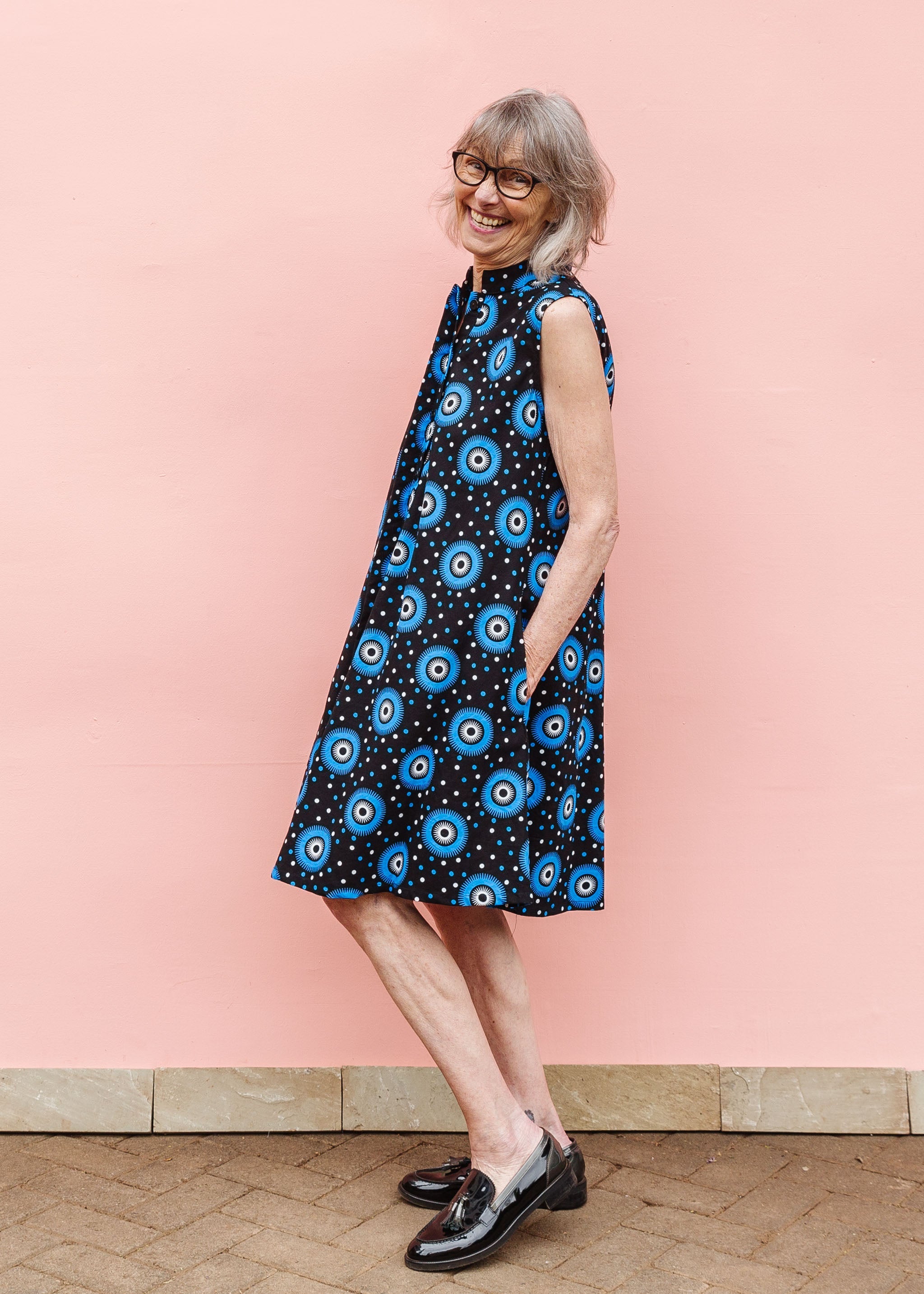 Model wearing black sleeveless dress with blue and white circle print.