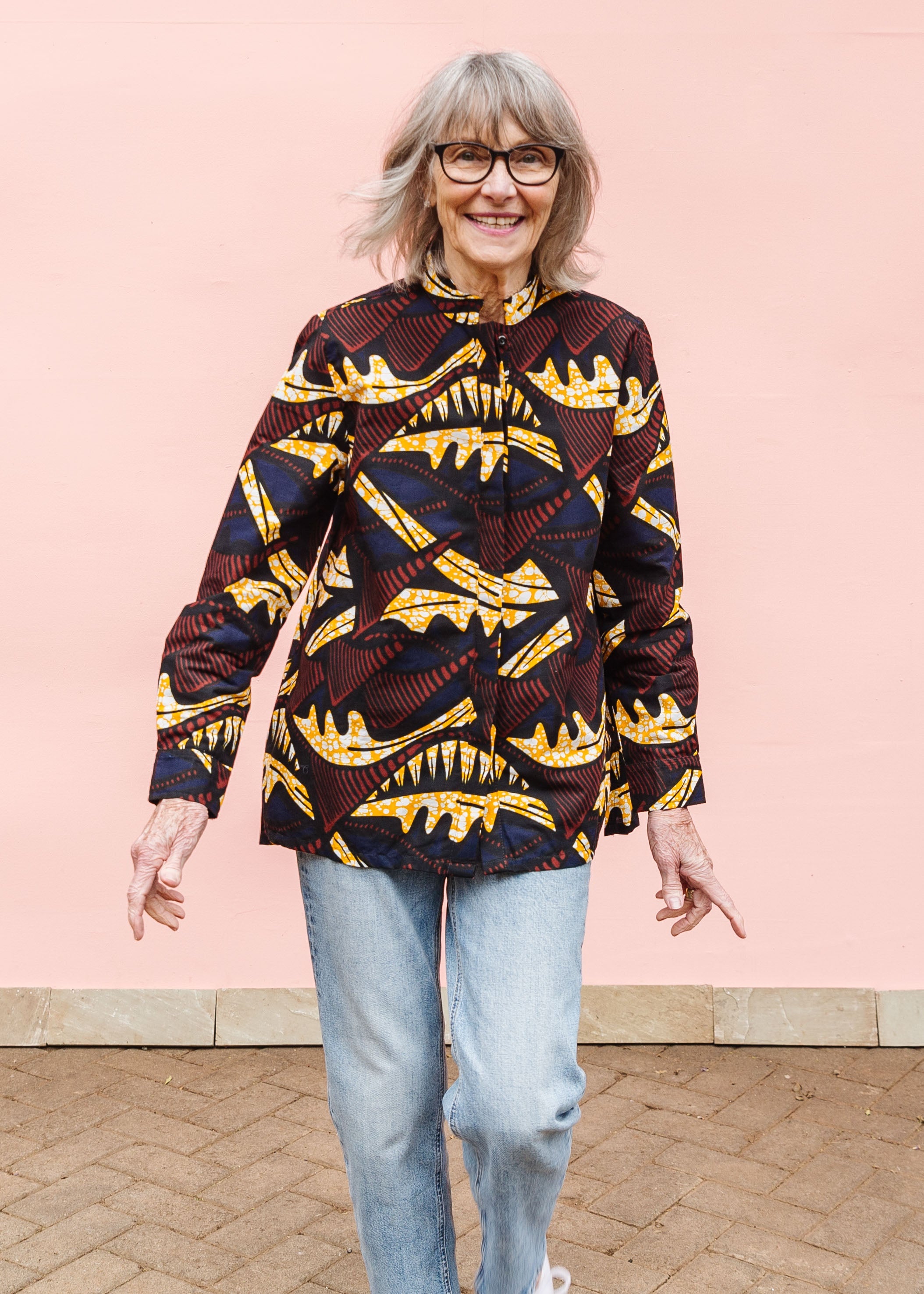 Model wearing long sleeve blouse with brown and yellow abstract print.