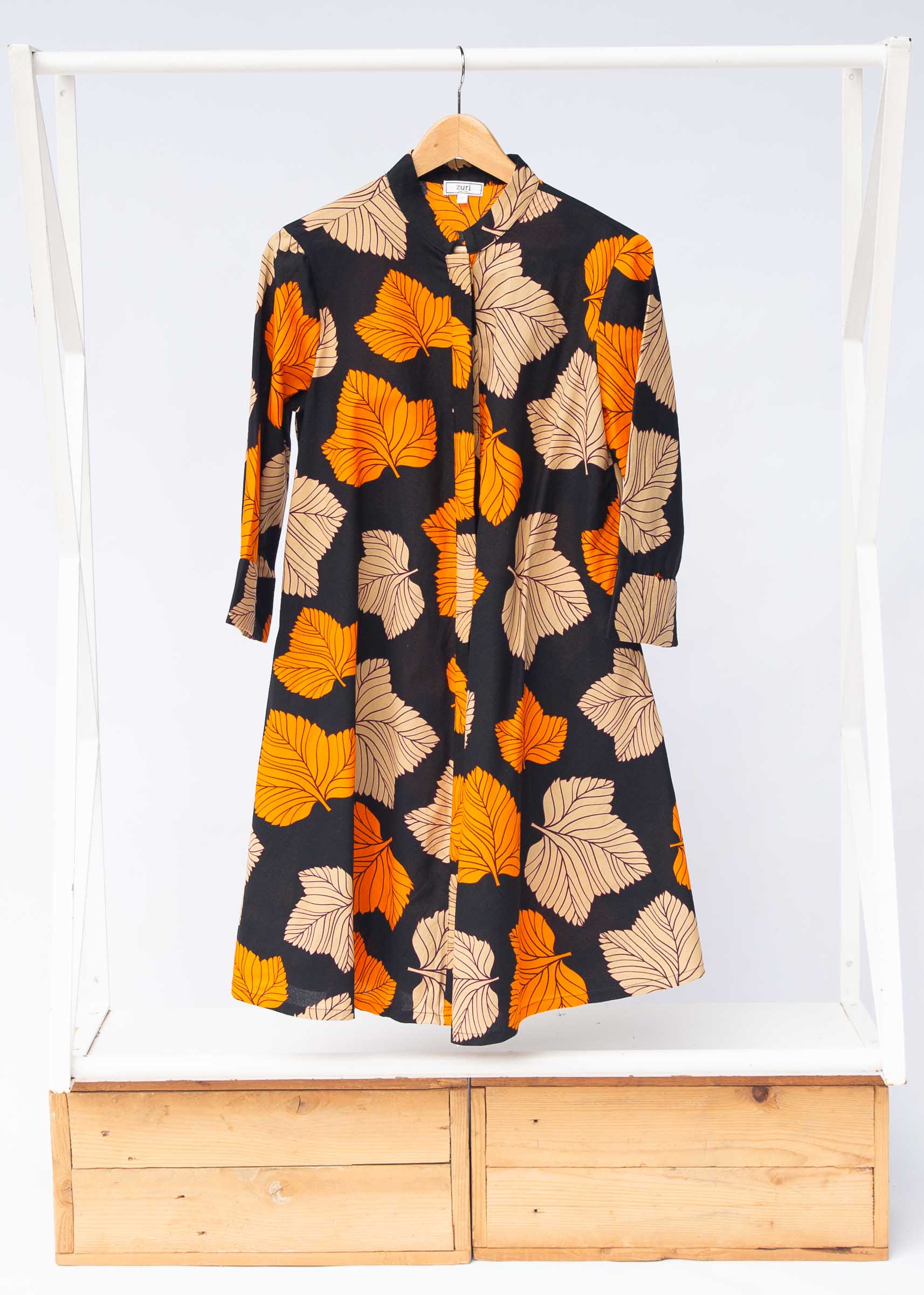 Display of orange, beige and black leaf print dress.